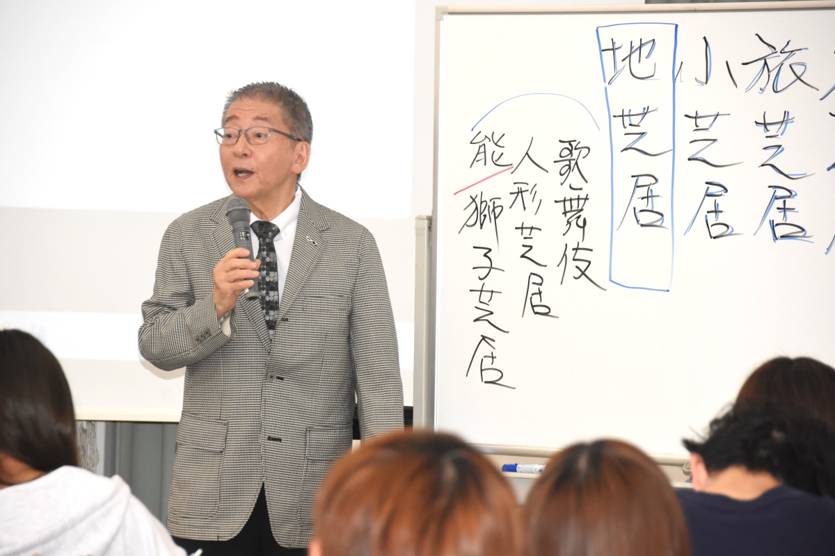 白板にペンで「大芝居、地芝居」と書き、古典芸能の歴史を分かりやすく解説する葛西氏
